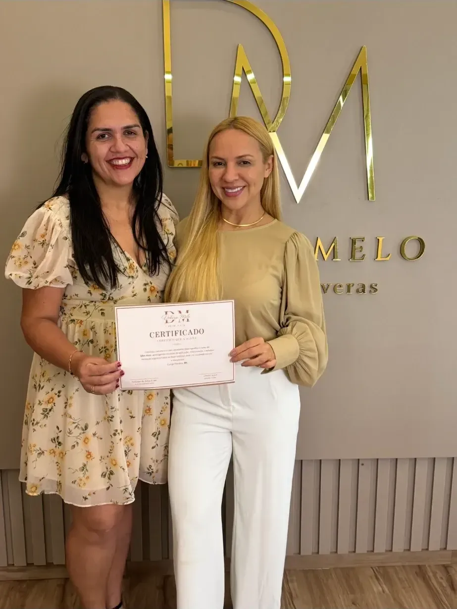 Aluna recebendo o certificado do curso Slim Hair das mãos de Débora Melo, no salão.