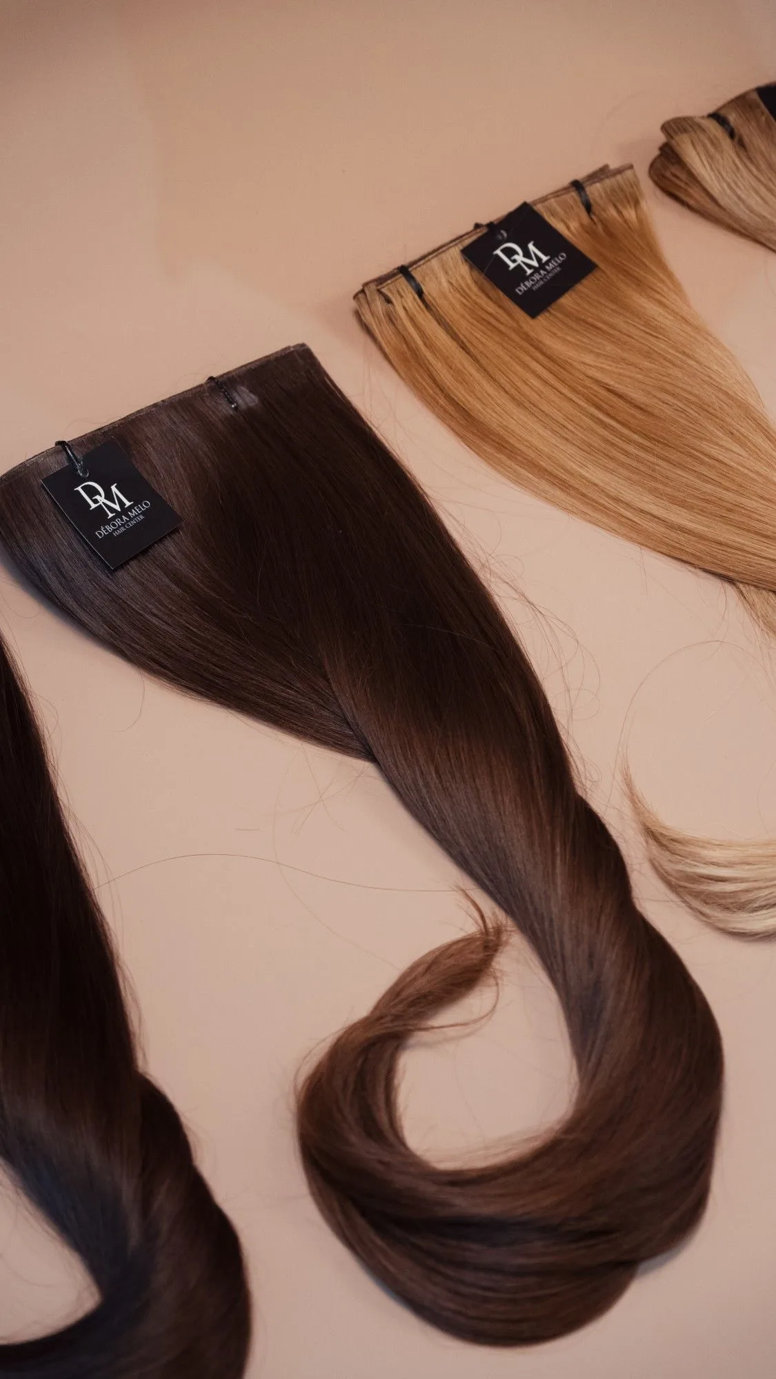 Mechas de cabelo castanho e loiro dispostas lado a lado, com etiquetas da marca.